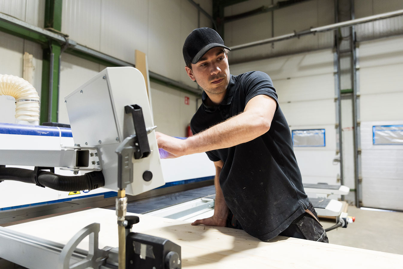 Schrijnwerker bedient zaagmachine in werkplaats tijdens houtbewerking